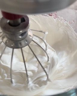 Un primo piano di un mixer con panna montata al suo interno.
