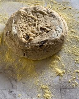 Un pezzo di pane è appoggiato su un tavolo ricoperto di farina.
