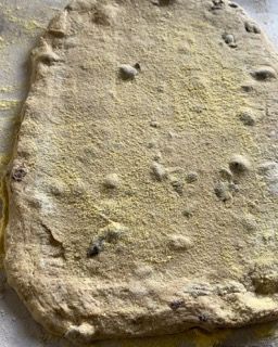 Primo piano di un pezzo di pasta ricoperto di zucchero a velo su un tavolo.