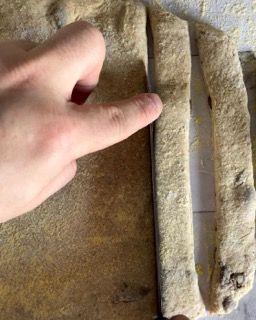Una persona sta tagliando un pezzo di pasta su un tagliere.