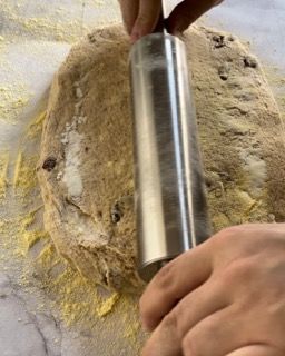 Una persona sta stendendo la pasta con un mattarello.