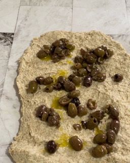 Un pezzo di pasta con sopra delle olive.