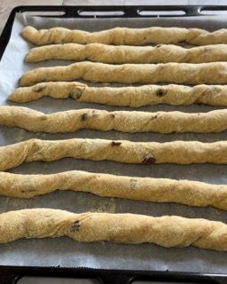 Un mucchio di grissini sono appoggiati su una teglia da forno