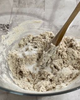 Un cucchiaio di legno è in una ciotola di farina