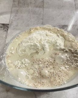 Una ciotola di vetro riempita con un composto di farina e liquido.