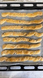 Un mucchio di grissini è appoggiato su una teglia da forno.