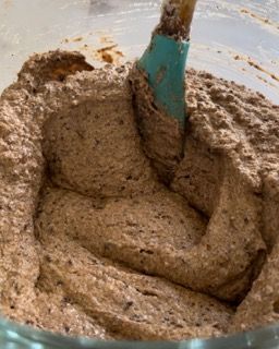 Primo piano di una ciotola di glassa al cioccolato con una spatola al suo interno.