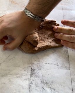 Una persona che indossa un orologio tiene in mano un pezzo di argilla