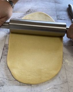 Una persona sta stendendo la pasta con un mattarello