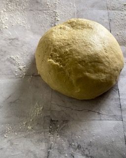 Una palla di pasta è appoggiata su una superficie di marmo.