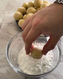 Una persona sta immergendo una pallina in una ciotola di farina.