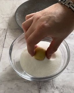La mano di una persona sta infilando la mano in una ciotola di zucchero