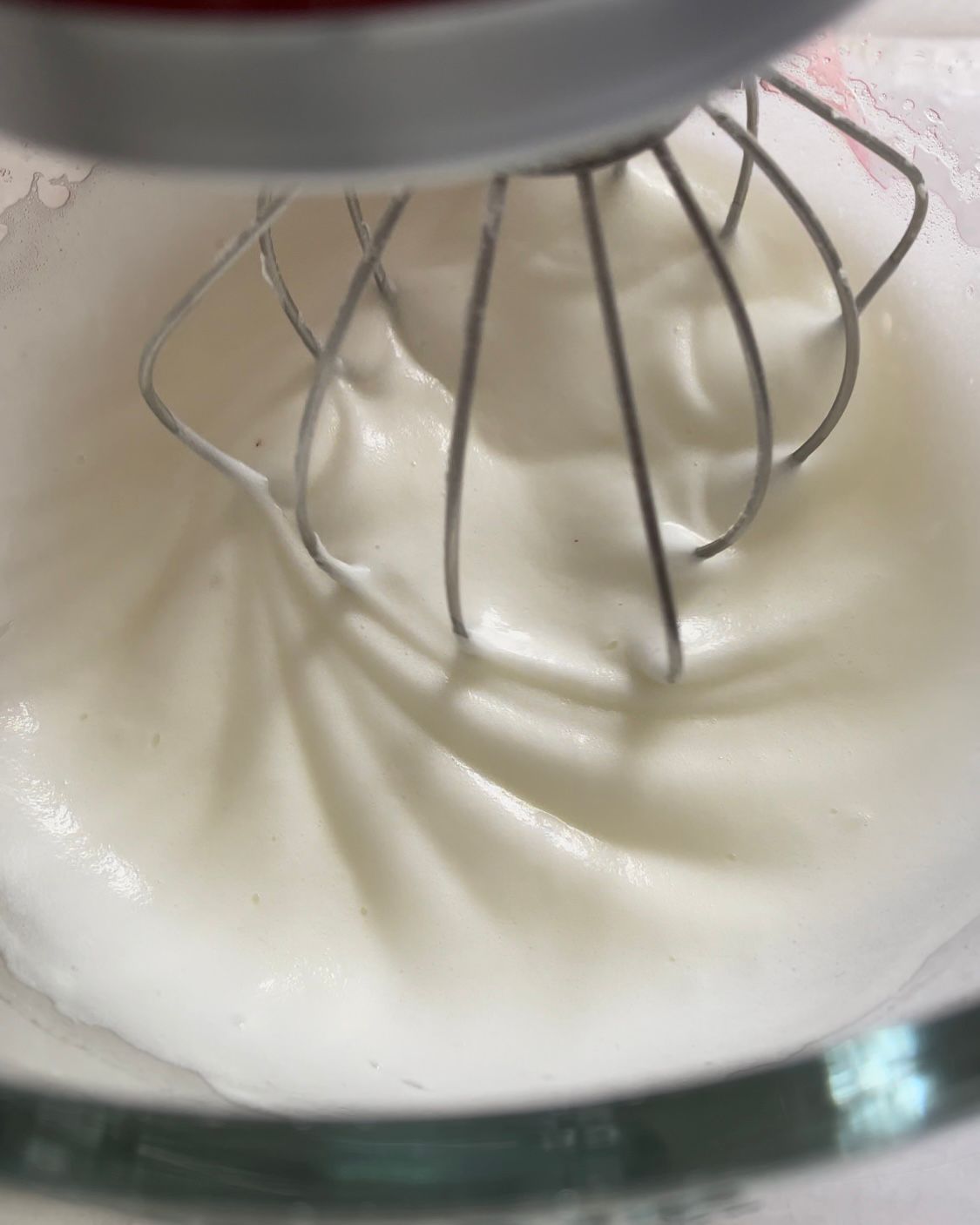 Un primo piano di una frusta in una ciotola di panna montata