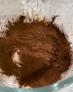 Una ciotola di vetro piena di cacao in polvere e panna montata.