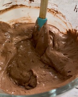 Una ciotola di glassa al cioccolato con una spatola dentro.