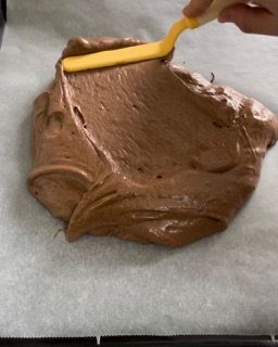 Una persona sta spalmando la glassa al cioccolato con una spatola gialla