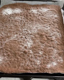 Una torta al cioccolato con zucchero a velo sopra è su una teglia.