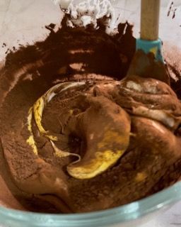 Una ciotola di impasto per torta al cioccolato con panna montata e una spatola