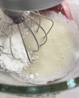 Un mixer mescola lo zucchero a velo in una ciotola di vetro.