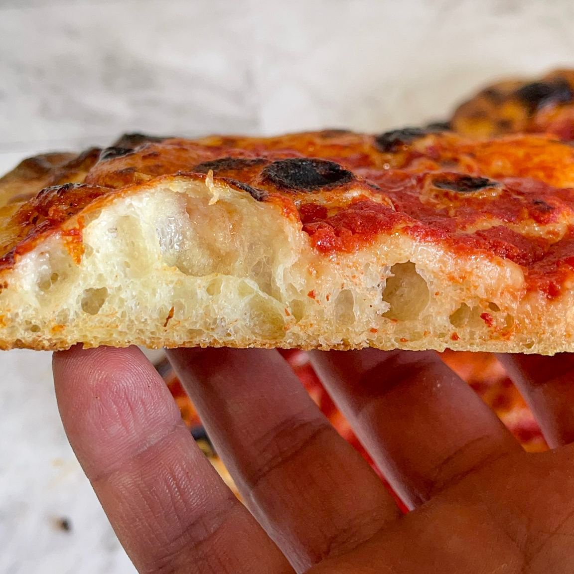 Una persona tiene in mano una fetta di pizza.