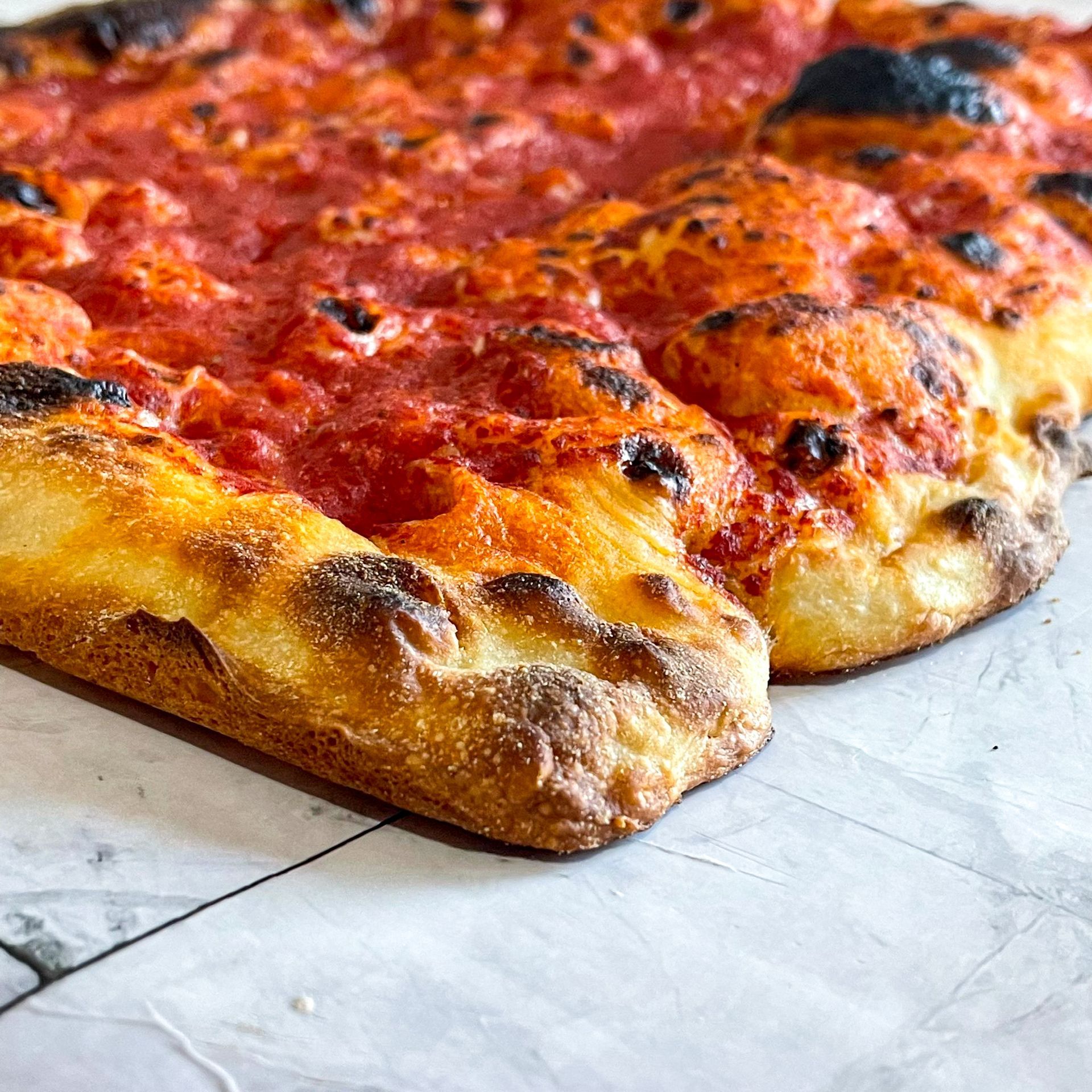 Una pizza con salsa di pomodoro e formaggio è appoggiata su un tavolo.