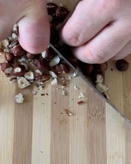 Una persona sta tagliando le noci su un tagliere di legno