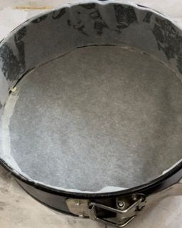 Una tortiera ricoperta di carta oleata è appoggiata su un tavolo.