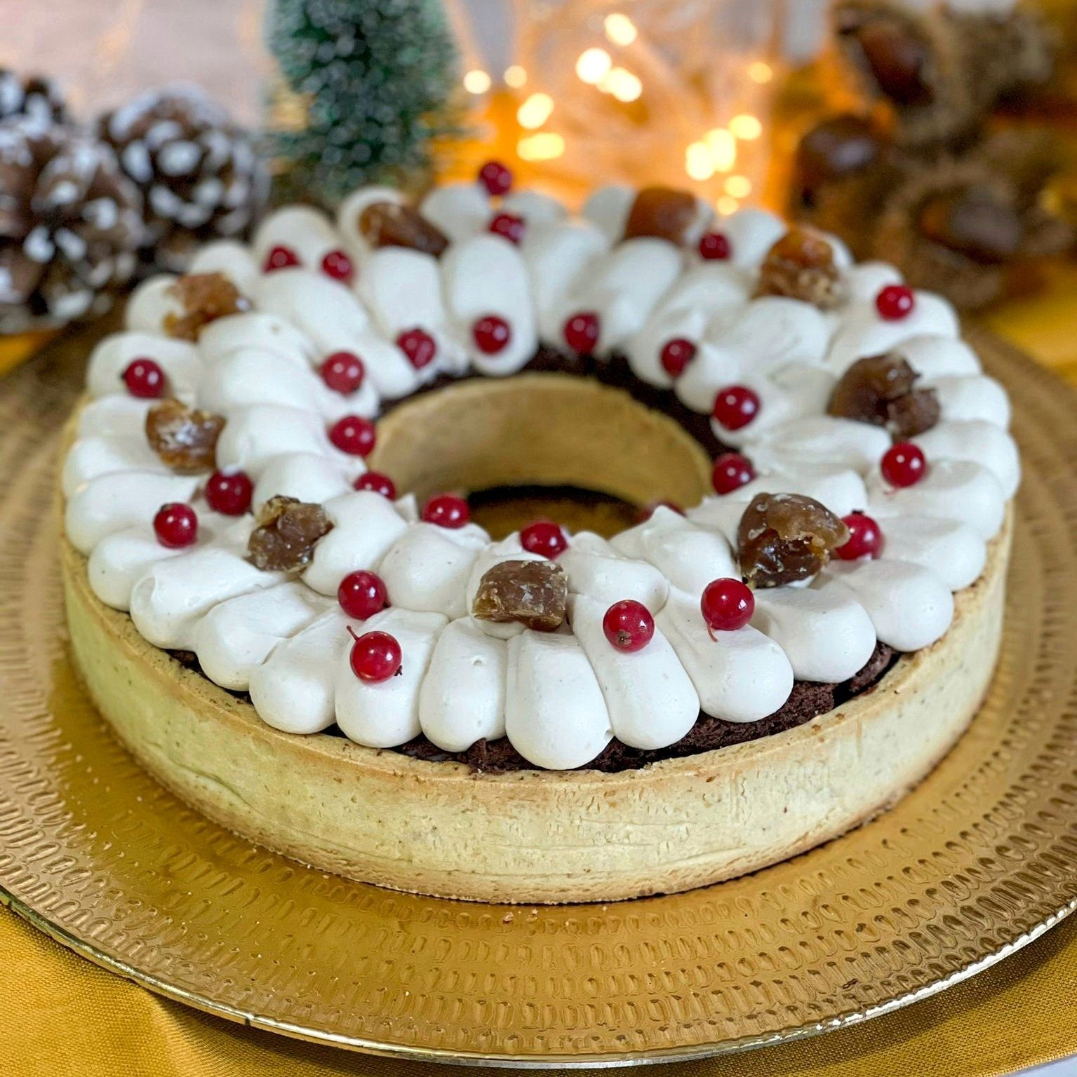 Una torta a forma di corona di Natale con panna montata e bacche rosse su un piatto.