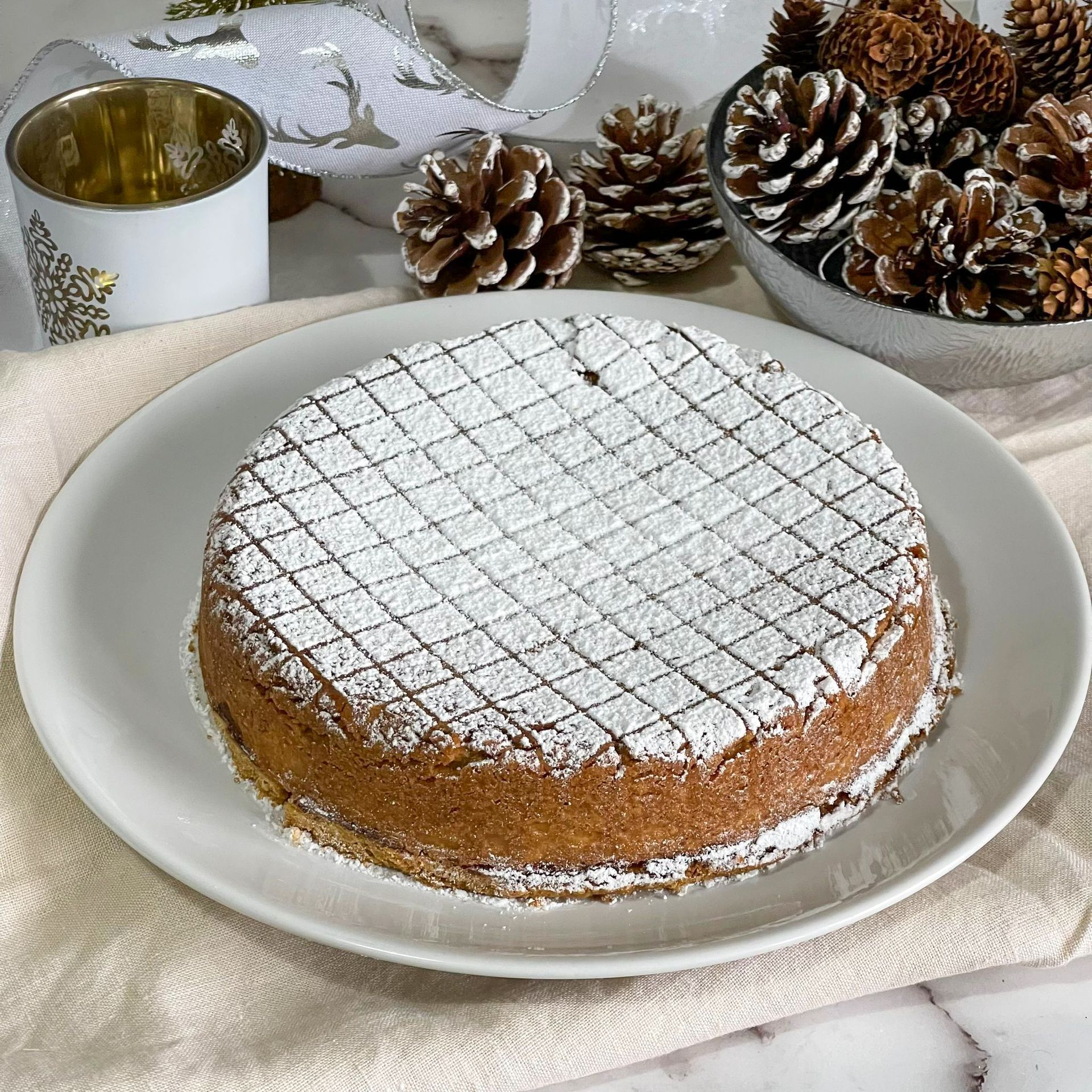 Un piatto bianco sormontato da una torta ricoperta di zucchero a velo