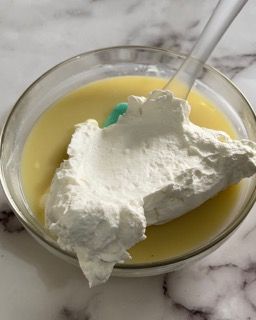 Una ciotola di budino con panna montata e un cucchiaio dentro.