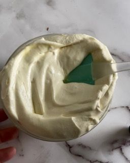 Una ciotola di panna montata con una spatola verde dentro.