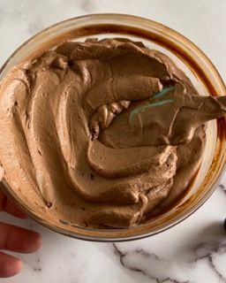 Una persona tiene in mano una ciotola di panna montata al cioccolato.