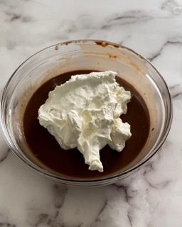 Una ciotola di budino al cioccolato con panna montata sopra.