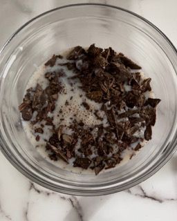 Una ciotola di vetro piena di gocce di cioccolato e latte su un tavolo.