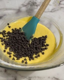 Una ciotola di cibo con gocce di cioccolato e un cucchiaio dentro