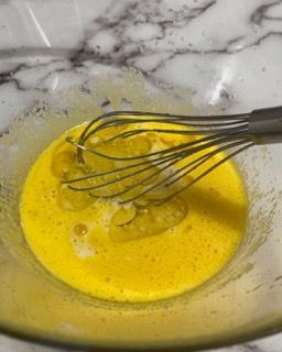 Una frusta è in una ciotola di liquido giallo.
