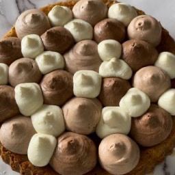 Un primo piano di una torta con cioccolato e glassa bianca su un tavolo.