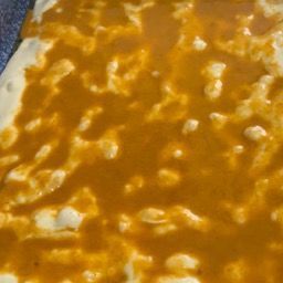 Primo piano di una casseruola piena di salsa e formaggio.