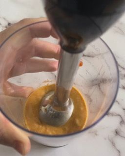 Una persona sta versando qualcosa in una ciotola con un frullatore.