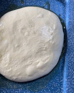 Un pezzo di pasta è appoggiato su una padella blu.