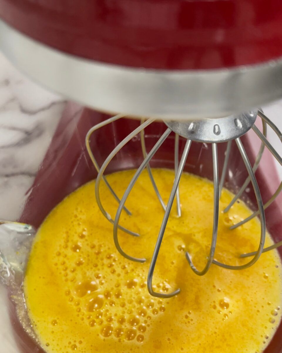 Un mixer rosso sta mescolando il liquido giallo in una ciotola