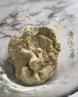 Un pezzo di pasta è appoggiato su una ciotola di vetro su un tavolo.