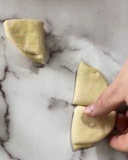Una persona sta tagliando un pezzo di pasta in tre parti.