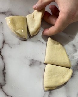 Una persona tiene in mano un pezzo di pasta su una superficie di marmo.
