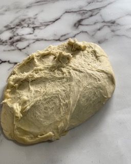 Un pezzo di pasta è appoggiato su una superficie di marmo.