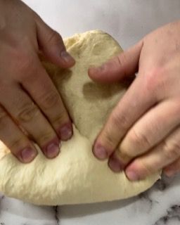 Una persona sta impastando un pezzo di pasta su un tavolo.