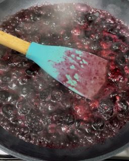 Una padella di salsa di frutti di bosco con una spatola dentro