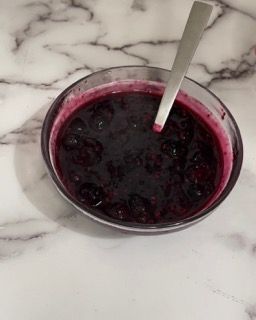 Una ciotola di salsa di mirtilli con un cucchiaio dentro