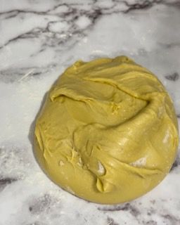 Una palla di pasta gialla è appoggiata su una superficie di marmo.