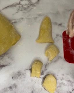 Una persona sta tagliando un pezzo di pasta su un tavolo.